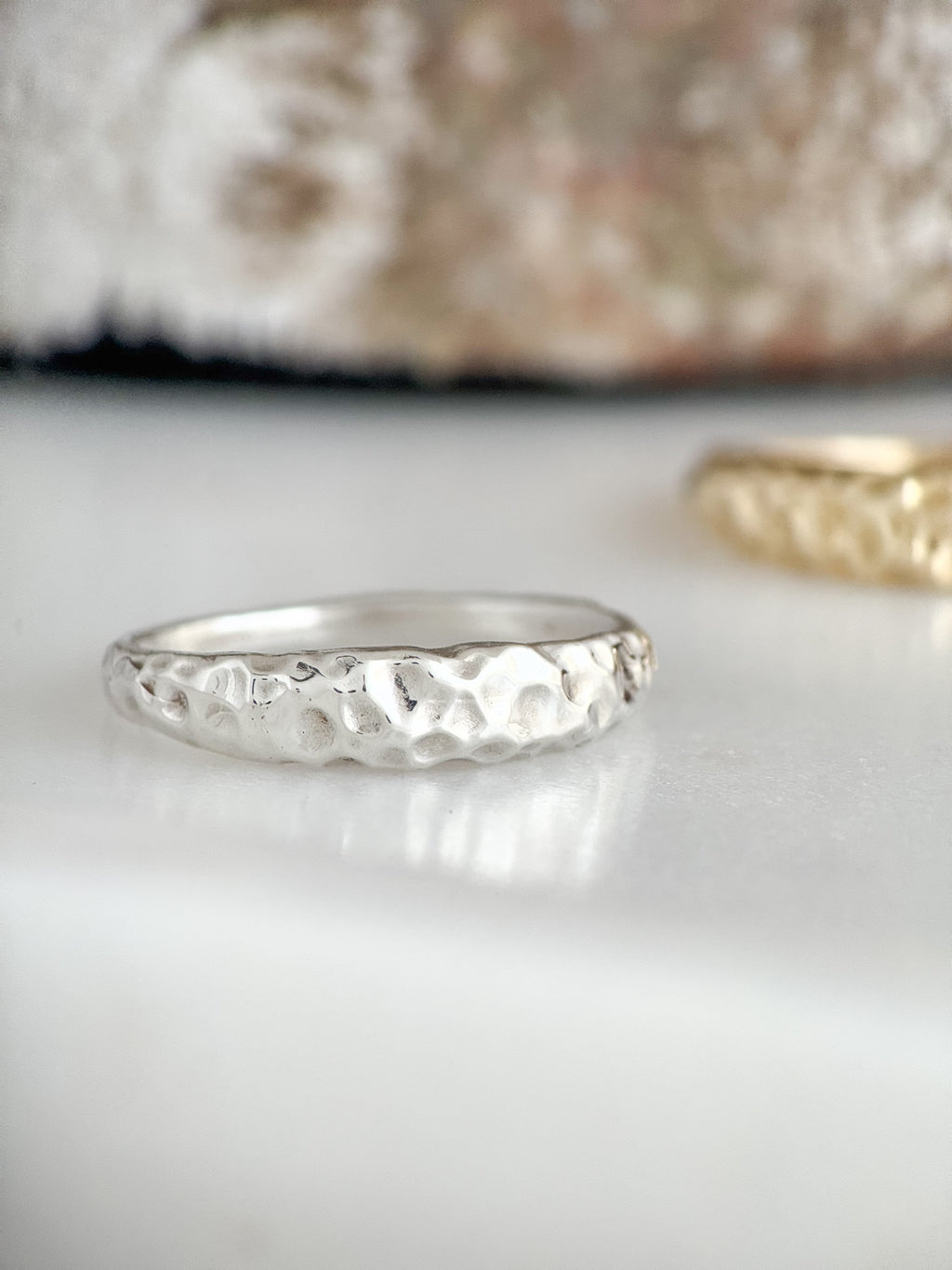 Silver ring with textured design on a white surface