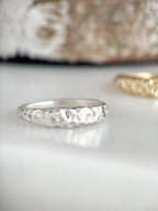 Silver ring with textured design on a white surface