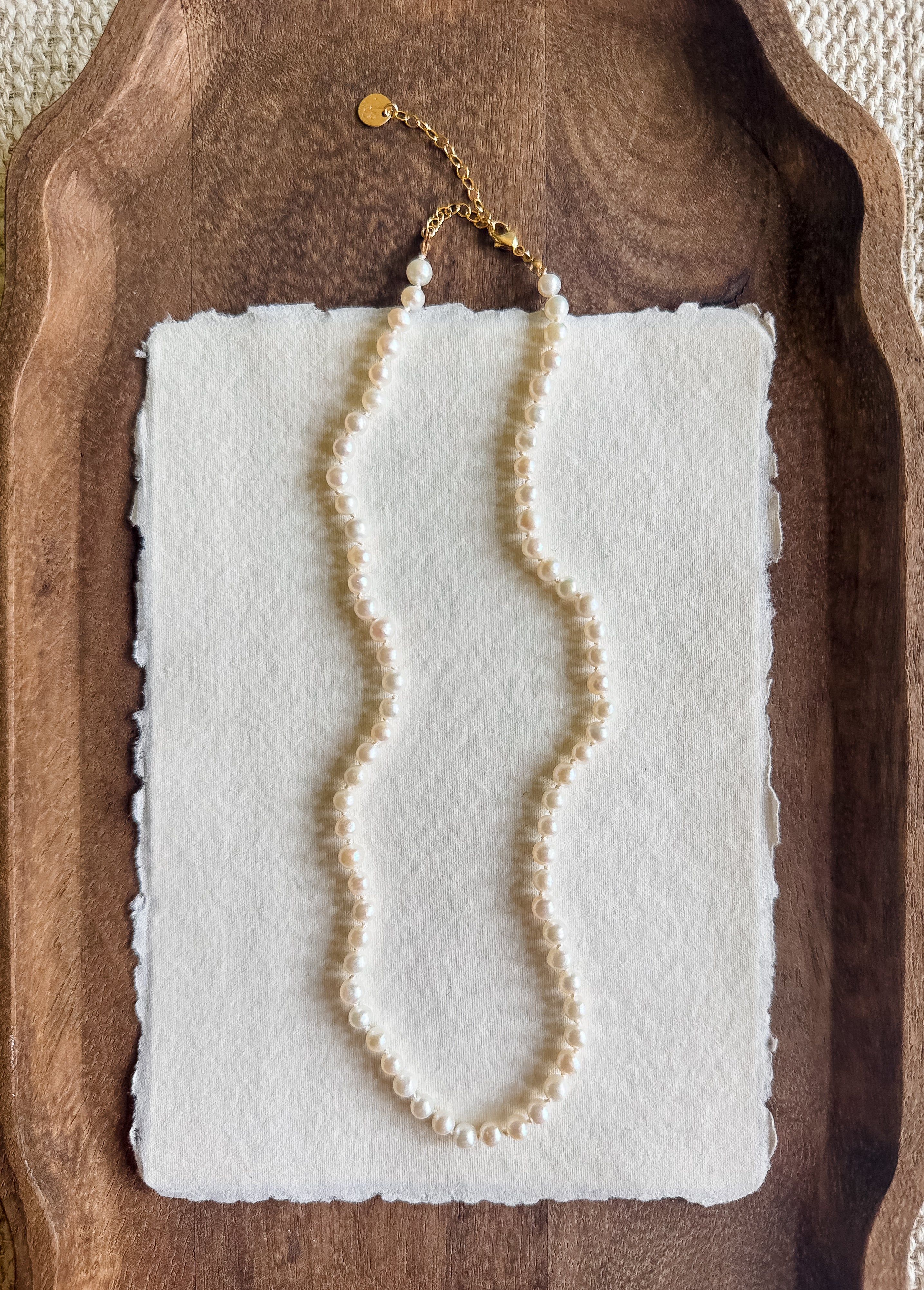 Pearl necklace on a white card with a wooden tray background