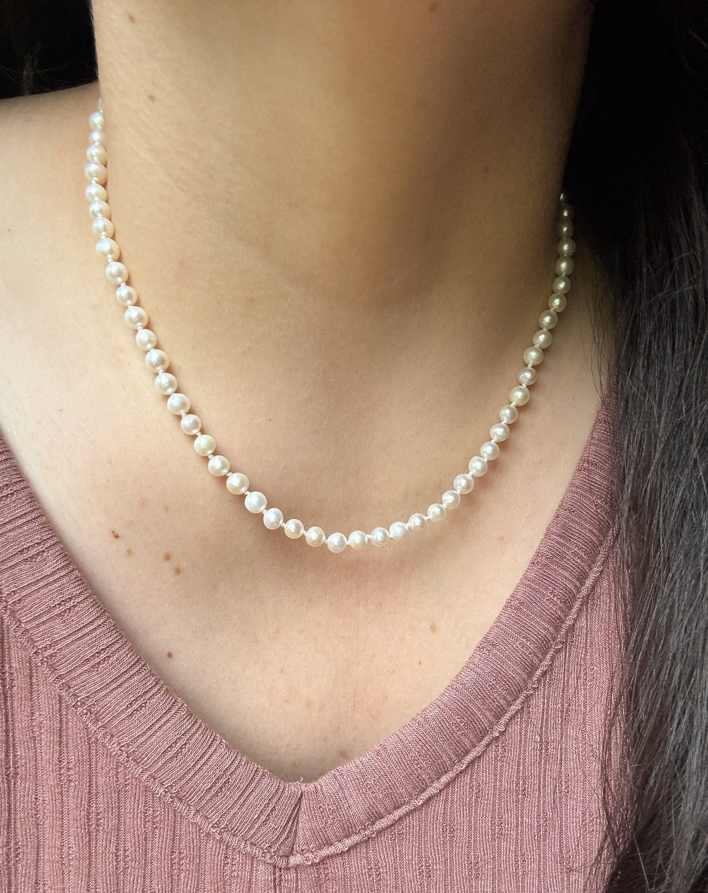 Pearl necklace worn by a person with a pink top