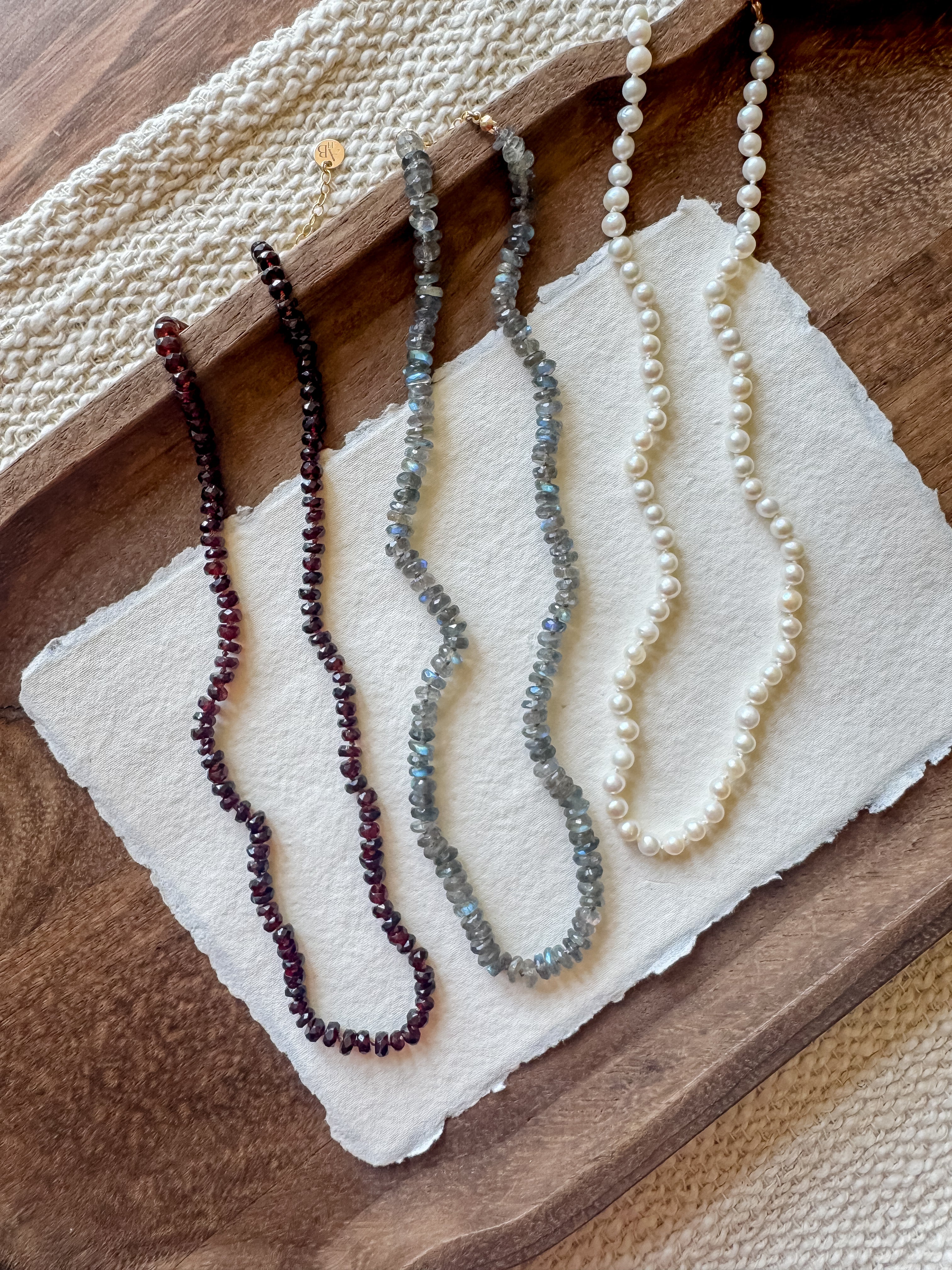 Three beaded necklaces on a textured white surface with a wooden background