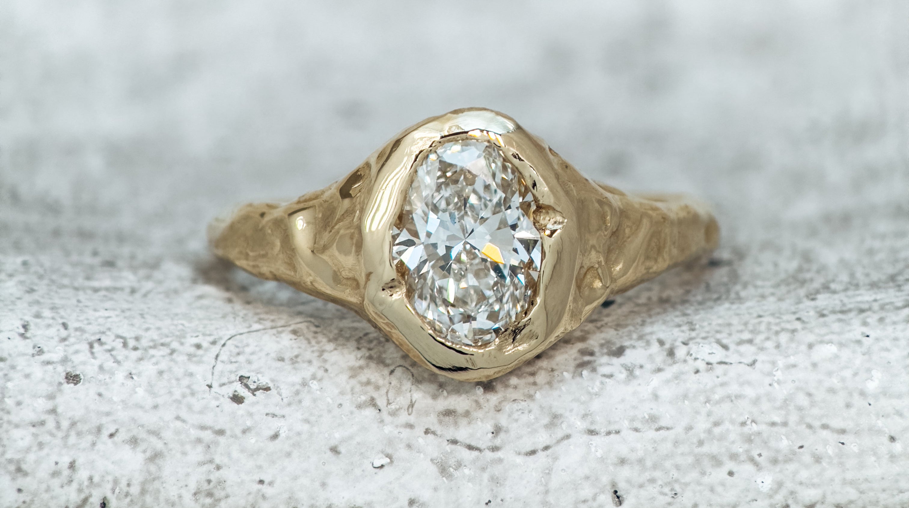 Gold ring with an oval diamond on a textured surface
